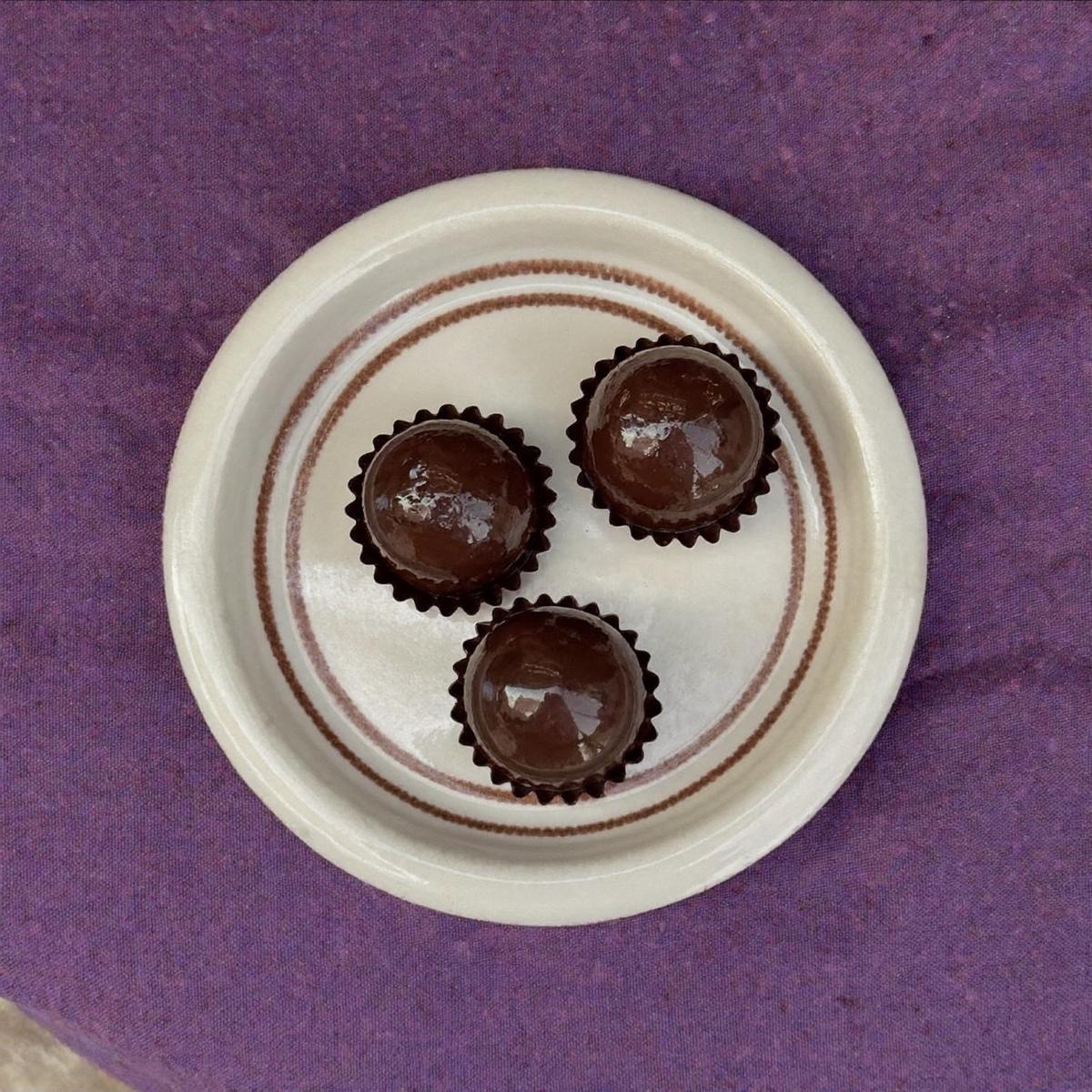 Three chocolate truffles on a small plate.