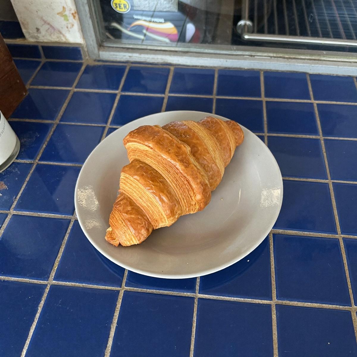 A single croissant on a plain plate.